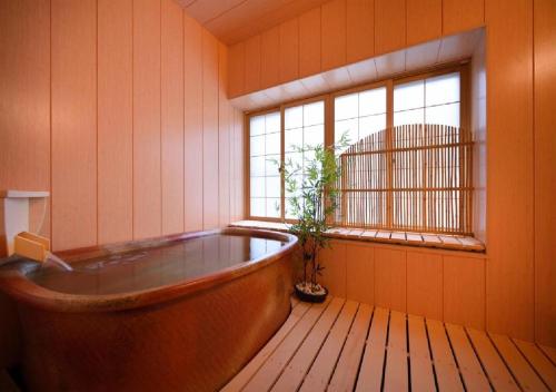 a bath tub in a room with a window at Dai Onsen Matsudaya Ryokan - Vacation STAY 67499 in Hanamaki
