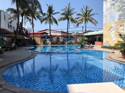 a large swimming pool with palm trees in a resort at Muong Thanh Quy Nhon Hotel in Quy Nhon