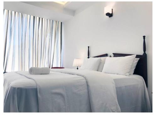 a bedroom with two beds with white sheets and a window at Bayfront in Weligama