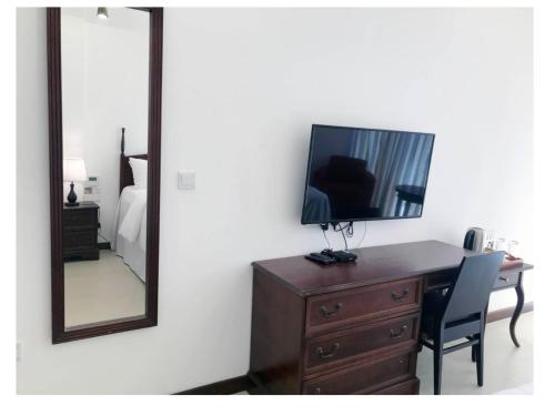 a bedroom with a dresser with a television and a mirror at Bayfront in Weligama