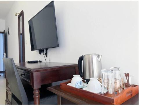 a desk with a television and a coffee maker on it at Bayfront in Weligama