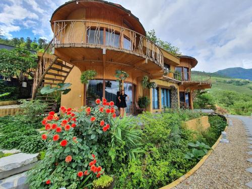 a person standing outside of a house with a balcony at Sapa Clay House - Mountain Retreat in Sa Pa