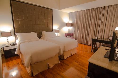 a hotel room with two beds and a television at Hotel Diradja in Jakarta