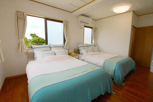 two beds in a room with two windows at Beach Side Secret in Ginoza