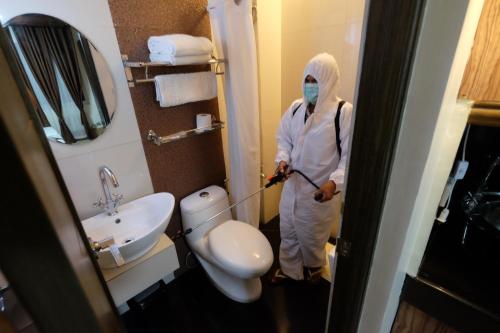 a person in a bathroom with a mop at Oriental Zen Suites in Manila