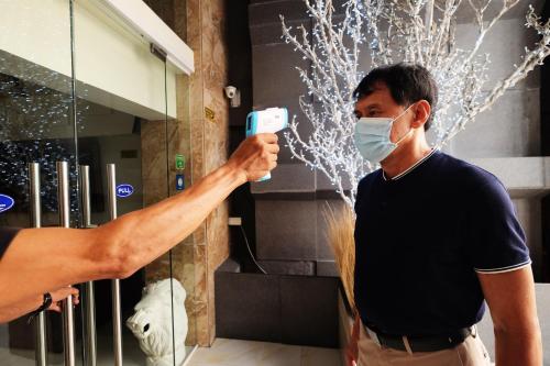 a man wearing a face mask holding a cell phone at Oriental Zen Suites in Manila