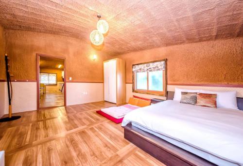 a bedroom with a large bed and a wooden floor at Angkure Pension in Seogwipo
