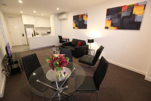 a living room with a glass table and chairs at Melbourne Knox Central Apartment Hotel Official in Wantirna