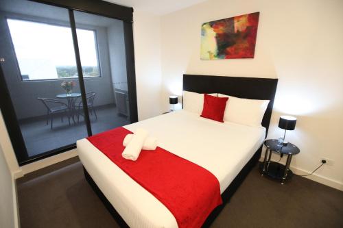 a bedroom with a large bed with a red blanket at Melbourne Knox Central Apartment Hotel Official in Wantirna
