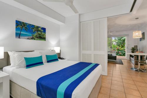 a bedroom with a large bed and a living room at Port Douglas Apartments in Port Douglas