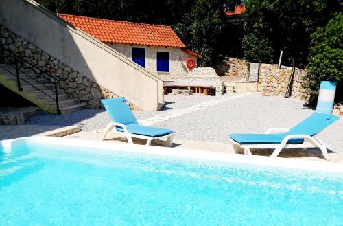 two blue chairs sitting next to a swimming pool at Maleluni in Malinska