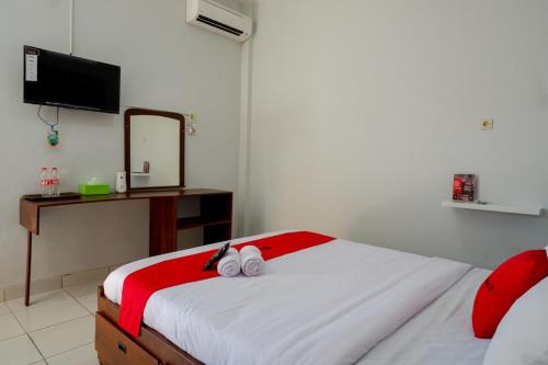 a bedroom with a bed with two shoes on it at RedDoorz near Padang Golf Adisucipto in Potrojayan