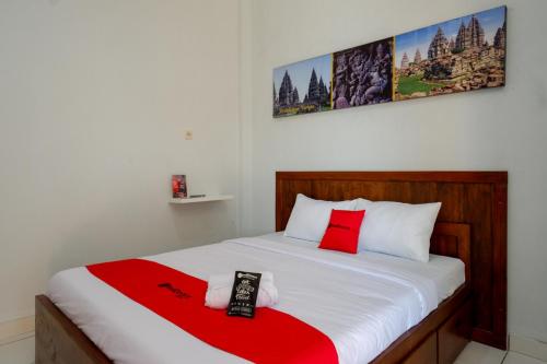 a bedroom with a bed with red and white sheets at RedDoorz near Padang Golf Adisucipto in Potrojayan