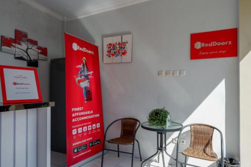a table and chairs in a room with a red poster at RedDoorz near Padang Golf Adisucipto in Potrojayan