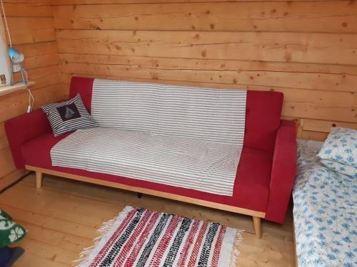 - un canapé rouge dans une chambre dotée d'un mur en bois dans l'établissement Prangli island Praaga Farmstay, à Lääneotsa