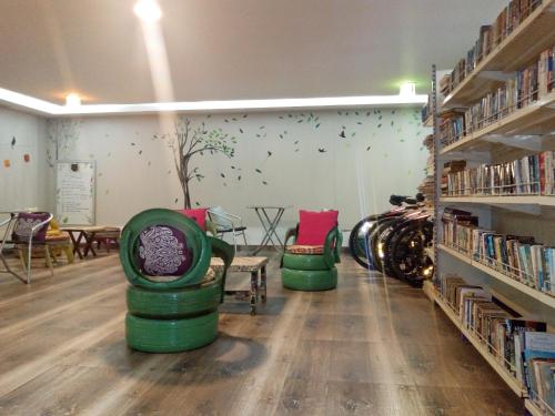 een bibliotheek met twee groene stoelen en een boom aan de muur bij Hotel Preethi Classic Towers in Ooty