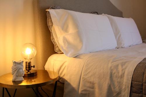a bed with a white pillow and a table with a lamp at Bed and Breakfast Terra del Sole Ibla in Ragusa