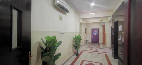a hallway with two plants and a purple door at Sama Sohar Hotel Apartments - سما صحار للشقق الفندقية in Sohar