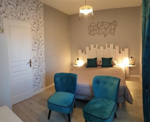 ein Schlafzimmer mit einem Bett und zwei blauen Stühlen in der Unterkunft la maison des oiseaux in Vandrimare