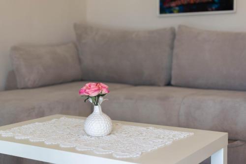 a vase with a pink rose sitting on a coffee table at Apartments Apartim Piran in Piran