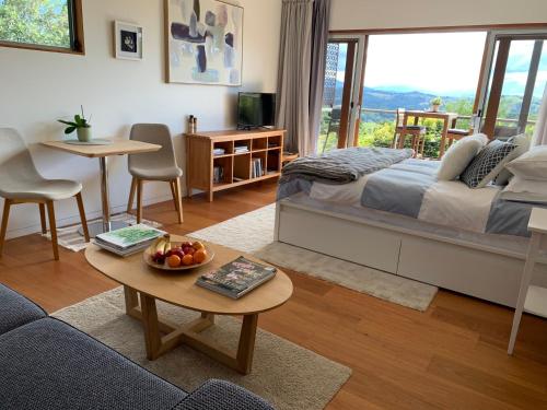 Un dormitorio con una cama y una mesa con un bol de fruta en Callemondah Studio with stunning views, in Bangalow and Byron Hinterland en Bangalow