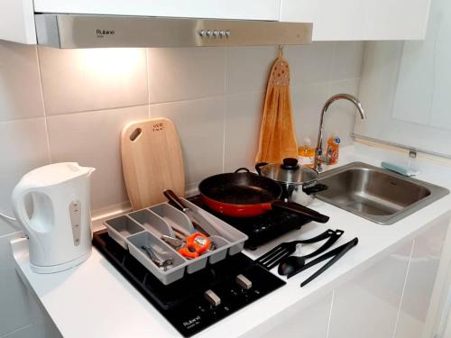 a kitchen counter with a stove top with a sink at Homey Galleria Suite A 10 12 in Seri Kembangan