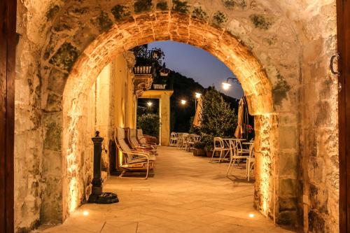 an archway in a stone wall with chairs and tables at Bed and Breakfast Terra del Sole Ibla in Ragusa