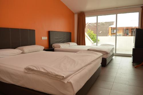 a hotel room with three beds and a large window at GF WONDERFUL HOTEL in Pontian Kecil