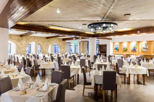 a banquet hall with white tables and chairs at Kefalos Beach Tourist Village in Paphos