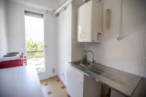 eine weiße Küche mit einem Waschbecken und einem Fenster in der Unterkunft +++++ brand new flat 4 persons near Hotel Martinez, center and Palais des festivals +++++ in Cannes