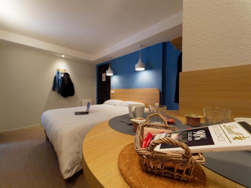 ein Zimmer mit einem Bett und einem Tisch mit einem Korb darauf in der Unterkunft Kyriad DIRECT Saint Brieuc - Parc des Expositions in Tregueux