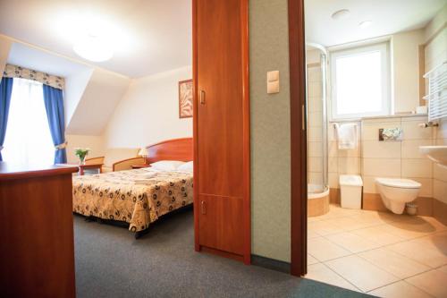 a bedroom with a bed and a bathroom with a toilet at Willa Gryf in Mielno