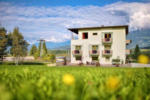 a white building with flowers in front of a field at B&B Garni Schorneck in Brunico