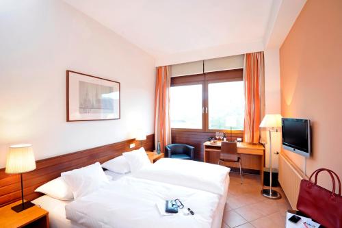 um quarto de hotel com uma cama, uma secretária e uma televisão em Michaelis Hof em Hamburgo