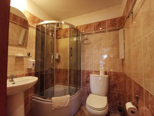 a bathroom with a shower and a toilet and a sink at Hotel Atlantis in Poznań