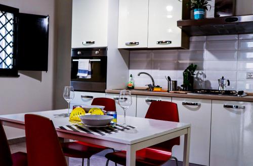 eine Küche mit einem weißen Tisch und roten Stühlen in der Unterkunft Trinacria apartments in Catania