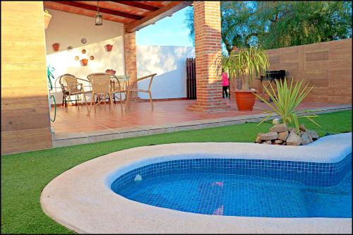 - une piscine dans une cour avec une table et des chaises dans l'établissement Chalet acogedor con piscina, à Conil de la Frontera