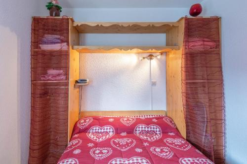 a bed with a wooden frame with a red bedspread at L'Arly in Flumet