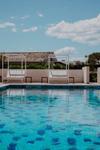 a swimming pool with chairs and blue water at Oustau Camarguen Hôtel & Spa in Le Grau-du-Roi