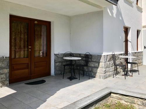 a patio with a table and chairs next to a door at Affittacamere Buenavista Guest House in Champoluc