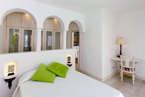 Dormitorio blanco con cama blanca y almohadas verdes en Villa Alegria, en La Oliva