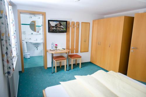 a bedroom with a bed and a table and a bathroom at Café Pension zum Jäger in Buchboden
