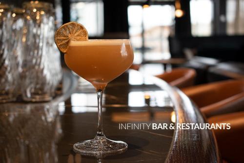 a cocktail sitting on a table with an orange slice at Infinity Hotel & Conference Resort Munich in Unterschleißheim