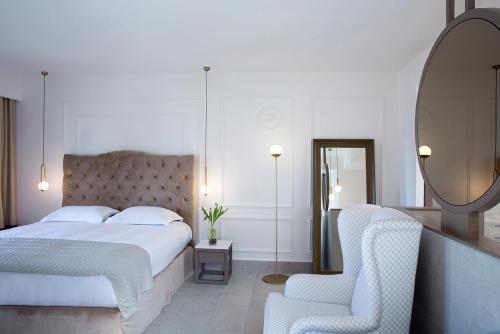 a bedroom with a bed and a mirror and a chair at Thalassa Boutique Hotel - Adults Only in Lassi