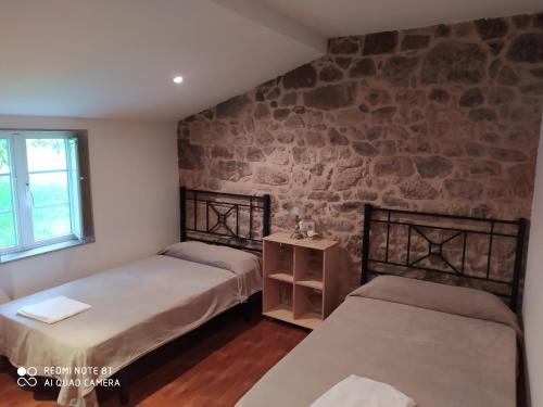 a bedroom with two beds and a stone wall at Pensión - Albergue de Logrosa in Negreira