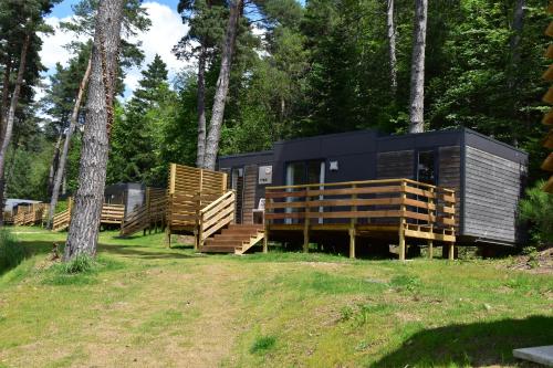 a black and wooden house in the woods at Camping Domaine du Lac Chambon in Murol