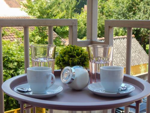 una mesa con tazas y platillos en el balcón en Quiet Center en Sremska Mitrovica