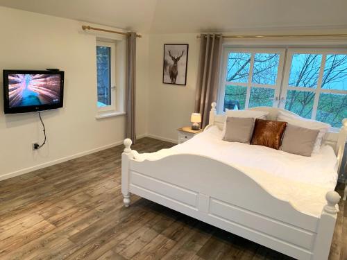 a bedroom with a white bed and a tv at B&B De Hooiberg Edam-Volendam in Edam