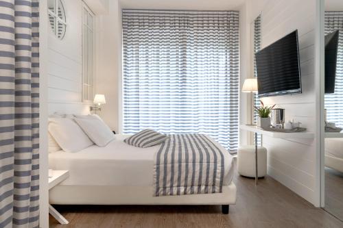 a white bedroom with a bed and a window at Hotel Panorama in Cattolica