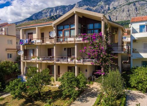 a building with flowers in front of a mountain at Apartments Agneza Tucepi in Tučepi